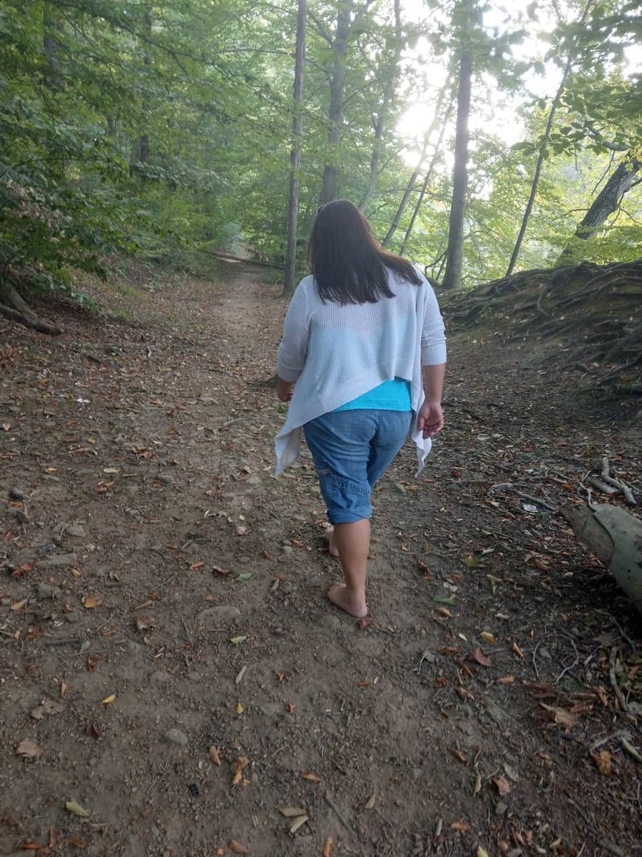 Jacqui hikes barefoot on a dirt covered trail in Bucks County, PA