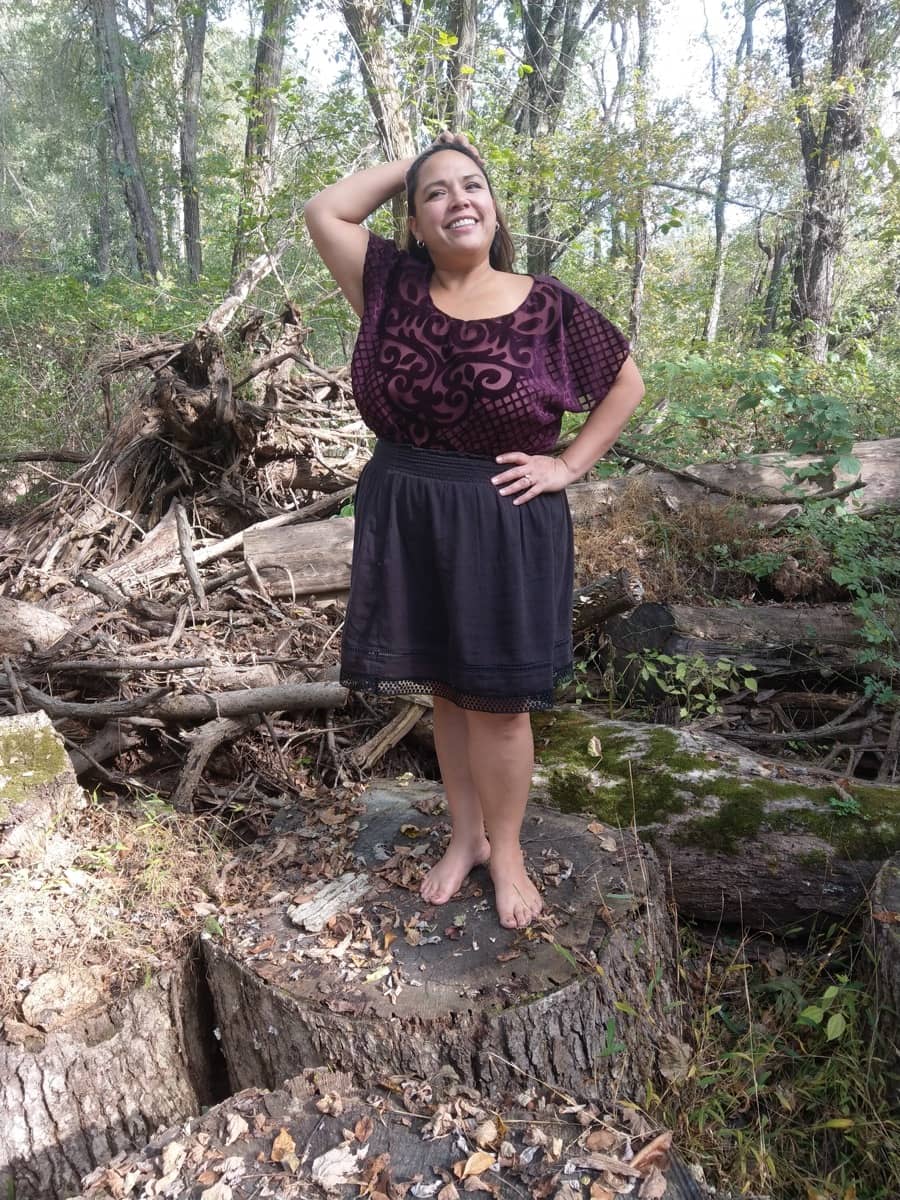 Jacqui poses on a tree stump while barefoot hiking