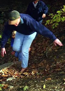 Barefoot hikers climb a steep and leafy slope